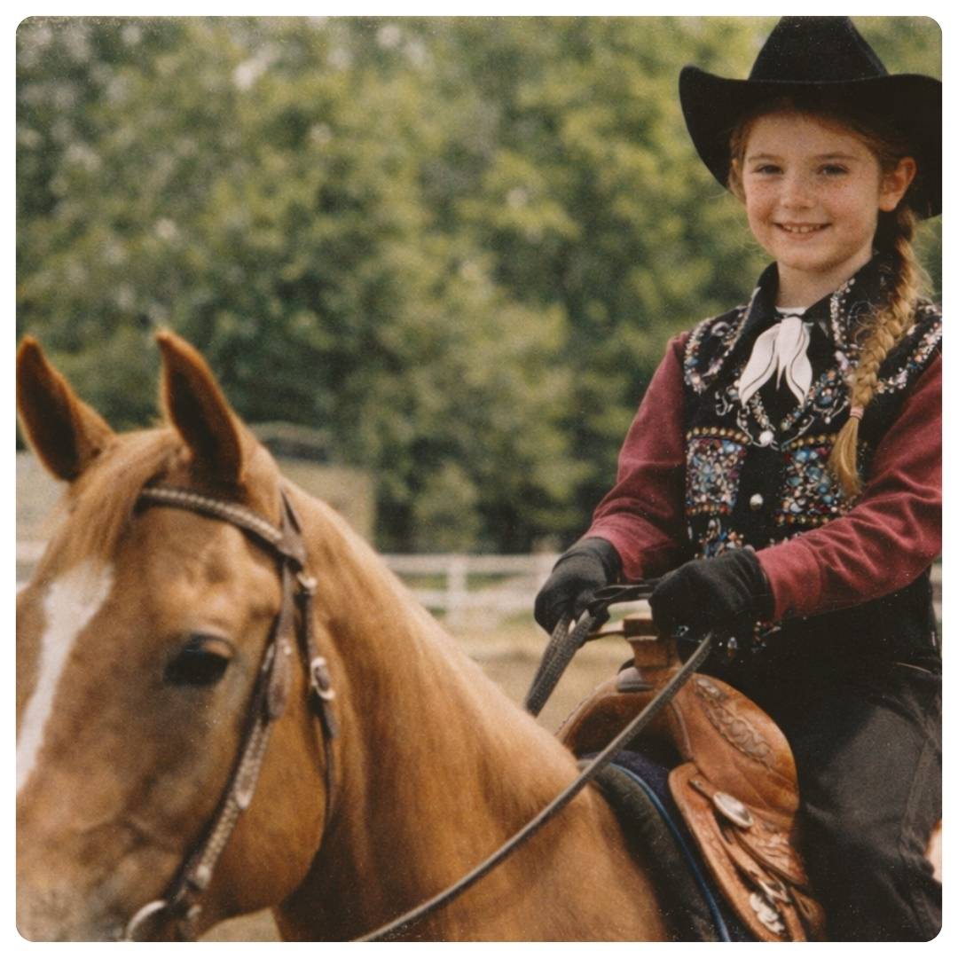 Young girl in a cowboy hat and vest sitting on a horse with a blurred green background